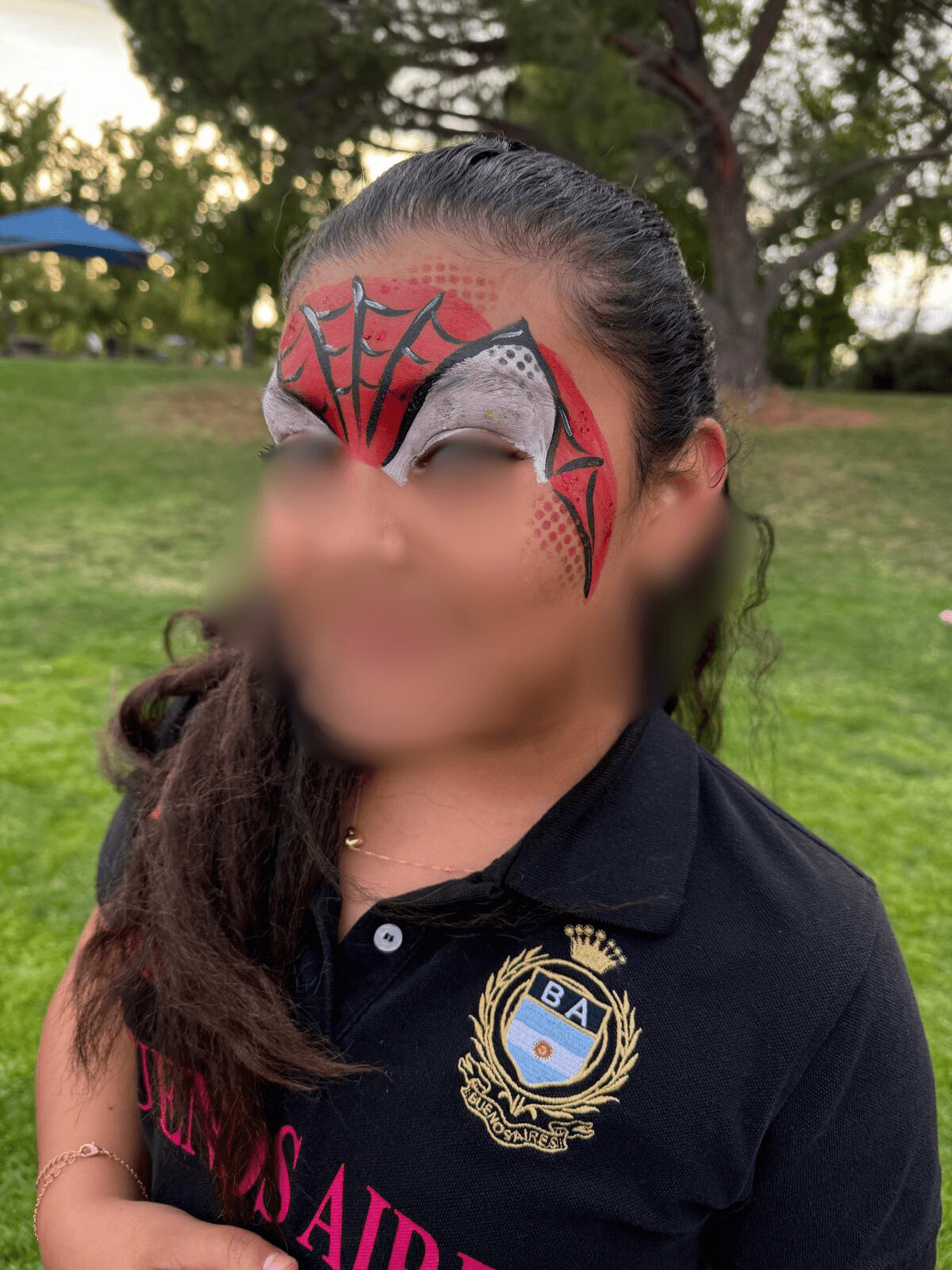 Spider-Man face paint design on forehead at an outdoor event